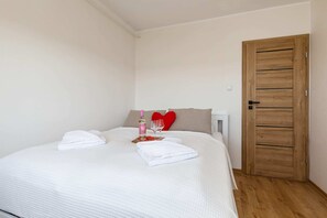 A cozy bedroom with a neatly made bed and simple decor, including wooden furniture.
