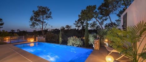 Vue de nuit de la piscine chauffée à débordement / Heated infinity pool.