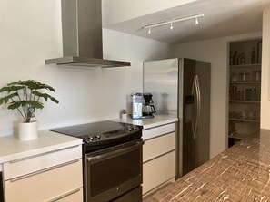 fully-stocked kitchen with stainless steel appliances & wine/beverage fridge  