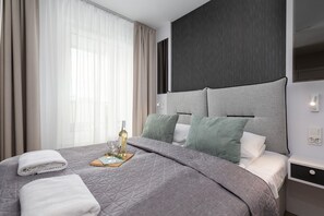 Comfortable bedroom featuring a gray upholstered bed and soft beige curtains, offering a relaxing ambiance.
