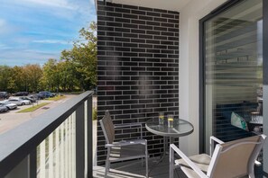 A balcony with a small outdoor seating arrangement and a view of the greenery.