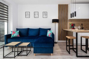 A living room featuring a blue sofa, a coffee table, and decorative wall art.
