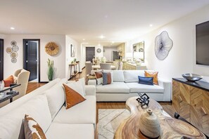 This open-concept dining room, living room, and kitchen space seamlessly blends comfort and style, creating an inviting atmosphere for family gatherings and entertaining. The spacious layout allows for effortless flow between the rooms, with a modern kitchen, cozy living area, and elegant dining space all coming together to offer both functionality and a warm, welcoming ambiance.