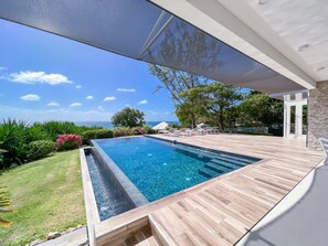 View from Wooden Terrace of Infinity Pool and Perfect Tropical Garden with Ocean in Back