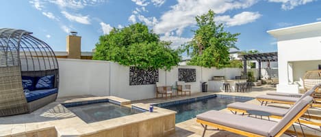 Curated backyard with a pool, hot tub, and plenty of lounge space.