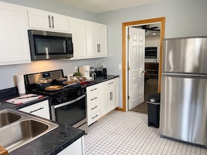 Kitchen stocked with cookware, dinnerware, silverware & stainless appliances.