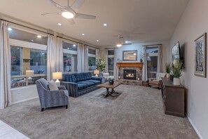 Beautiful great room with natural gas fireplace and TV has views of the backyard paradise.