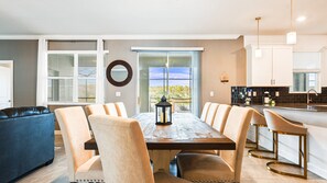 Spacious dining area with seating for 10 and scenic poolside views beyond.