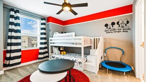 Fun-filled kids' room with bunk beds, trampoline, and cheerful Disney decor.