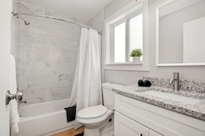Luxury Bathroom Featuring Porcelain Tile, Granite Countertops, and Plush Towels