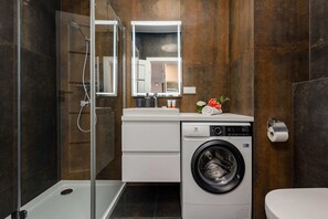 Bathroom with a shower, toilet and washing machine.