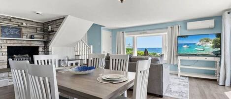 open kitchen & living room with sleeper sofa, 50" smart TV, high-efficiency mini-split for AC/heat, and stunning views of the ocean.
