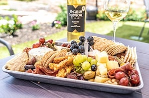 A charcuterie board pairs well with a glass of wine and features a tantalizing spread of savory meats, creamy cheeses, fresh fruit, crisp crackers, briny olives, and crunchy nuts.