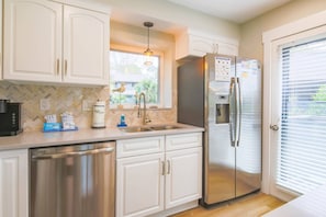 The newly renovated kitchen features white cabinetry and a herringboned tiled backsplash.