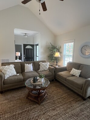 Comfortable living room with TV, gas fireplace, work station and ceiling fan.