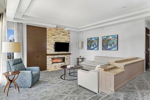 Separate living area features a sleeper sofa, flat screen TV, and door to the furnished balcony.