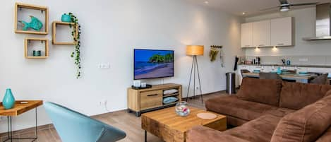 Conjunto de salón con smart TV de 50 pulgadas en salón con cocina abierta.