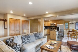 Living Area- The open floor plan connects the living room, kitchen, and dining room. - Photo taken from living room showing beige couch, looking into kitchen