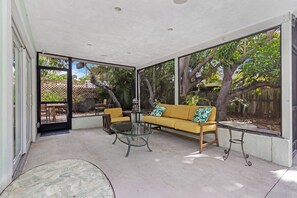 [Back] Screened-in back porch with lounge area. Door leads into backyard patio.