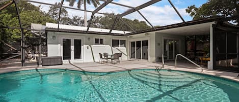 [Backyard] Screened-in heated pool with lounge area.
