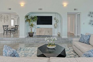 Escape to tropical bliss in our spacious living room, adorned with vibrant decor and centered around a large TV for ultimate relaxation.