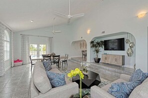 Bask in the inviting glow of natural light in our spacious living room, accentuated by tropical decor and a large TV for your enjoyment.