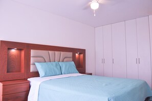 Main bedroom with a queen bed, two night tables, lamps and closets