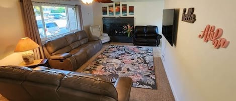 Living room featuring 65" smart tv and reclining sofas.