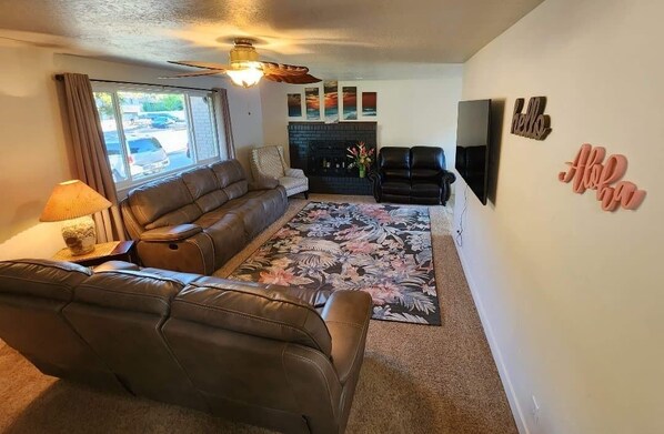 Living room featuring 65" smart tv and reclining sofas.