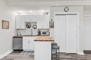 Galley kitchen with electric stove top, microwave, mini fridge.