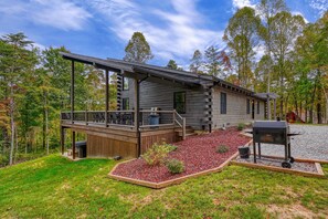 Covered porch with patio tables, corn hole game and charcoal grill