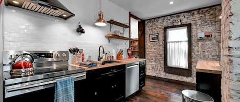 Modern kitchen with original brick walls and hardwood floors. 