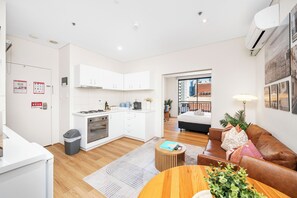 Step into your vibrant urban sanctuary! This spacious studio apartment features a fully equipped kitchen with a stovetop and oven, a cozy living area with a comfortable leather sofa, and direct access to your private sleeping space. 