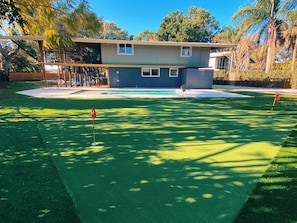 Backyard with pool and putting green.