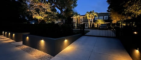 Gated entry well lit up with landscape lighting 