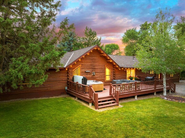 The back patio and hot tub overlooks a large lawn and private stretch of water.