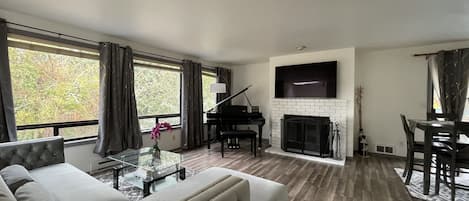 Brightly lit, open concept floor w/ living room & dining area, piano & fireplace