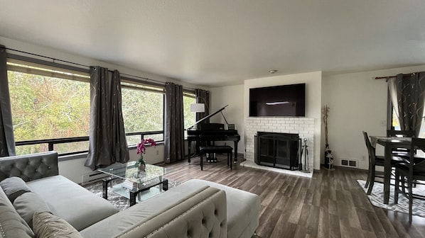 Brightly lit, open concept floor w/ living room & dining area, piano & fireplace