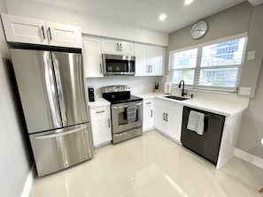 Brand new kitchen with white quartz countertops and solid wood cabinets