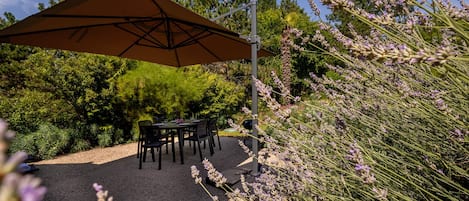 Terrasse privée  avec 2 chaises longues, tables, chaises, bbq et parasol