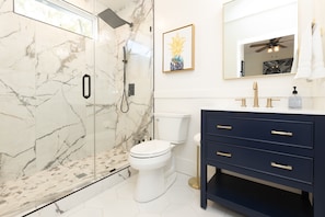 Bathroom #1 with floor to ceiling porcelain tile walk-in shower with an oversized rainfall shower head and handheld shower feature, large in-shower window and vanity.