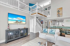Living room. Door open to Master King bedroom. Kitchen and stair access to 2nd floor