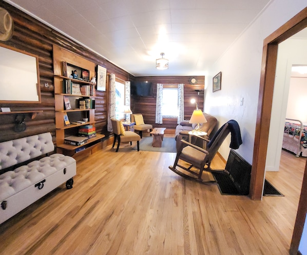 Living room with TV, couch, chairs, rocking chair and fancy bench. 