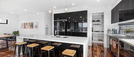 Modern kitchen and open plan living dining space flows out to balcony