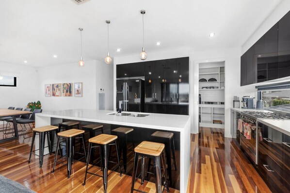 Modern kitchen and open plan living dining space flows out to balcony