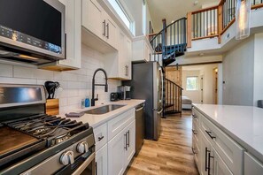 The space features a fully equipped kitchen on the main floor, with stairs leading up to a loft area.