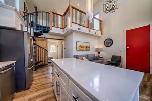 The home entrance features a living area, a fully equipped kitchen, and a set of stairs leading up to the loft.