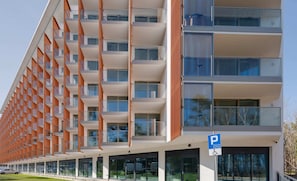 A view of the modern apartment building with orange accents and glass balconies.