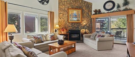 Enjoy the open-space living area as you relax in one of the three cozy sofas while taking in the high ceilings, impressive stone-finished fireplace, and views out the large windows.