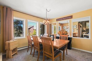 The intimate dining area with a table and seating for six next to a wall of windows looking straight out into the trees.